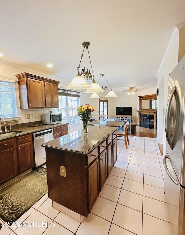 22 Enclosure Dr, Morganville, NJ 07751 - kitchen with appliances with stainless steel finishes, a fireplace, a ceiling fan, a kitchen island, and backsplash