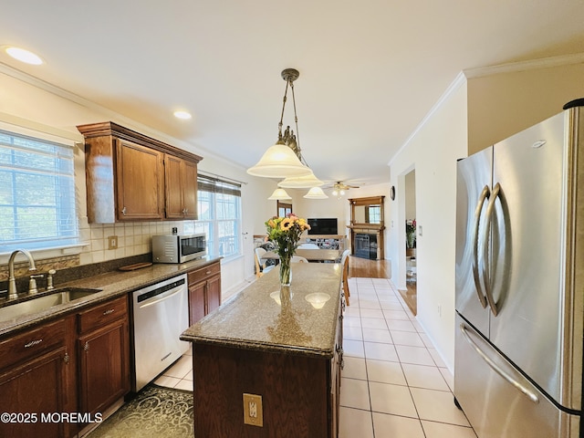 22 Enclosure Dr, Morganville, NJ 07751 - kitchen featuring stainless steel appliances, a glass covered fireplace, ornamental molding, a kitchen island, and dark stone counters