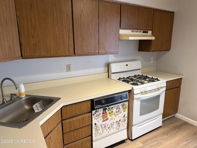 87 Puffin Glade, Berkeley, NJ 08721 - kitchen featuring under cabinet range hood, white gas stove, dishwasher, a sink, and light wood finished floors