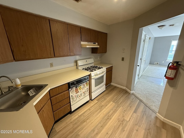 87 Puffin Glade, Berkeley, NJ 08721 - kitchen with under cabinet range hood, white gas stove, dishwasher, a sink, and light wood-style flooring