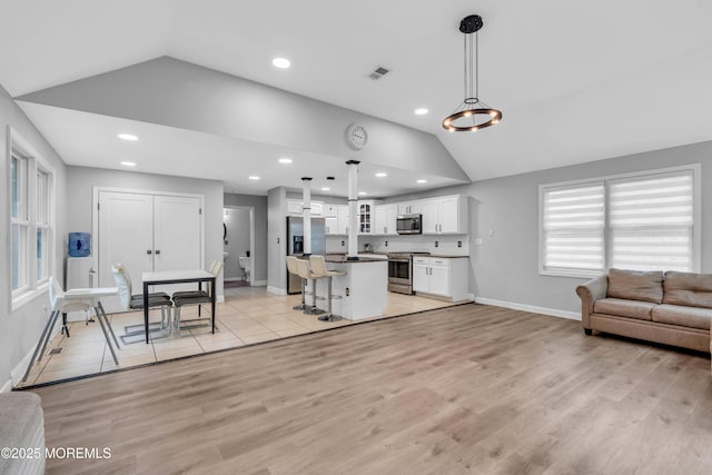 137 Willow Dr, Jackson, NJ 08527 - kitchen with appliances with stainless steel finishes, vaulted ceiling, white cabinets, open floor plan, and a center island