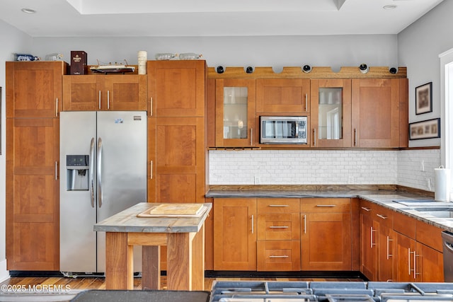1639 Bay Blvd, Ortley Beach, NJ 08751 - kitchen with appliances with stainless steel finishes, brown cabinetry, backsplash, wood finished floors, and glass insert cabinets