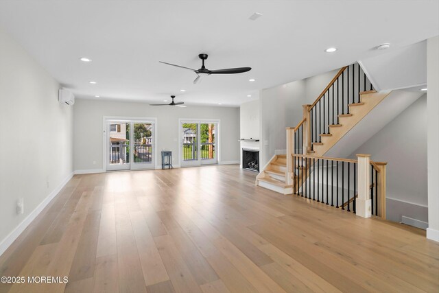 72 4th St, Highlands, NJ 07732 - unfurnished living room with a wall mounted air conditioner, a fireplace, wood finished floors, ceiling fan, and stairs