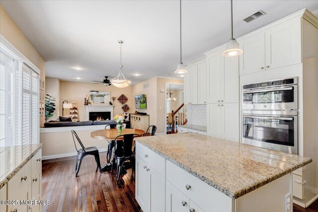 10 Unity Ct, Middletown, NJ 07748 - kitchen featuring double oven, a lit fireplace, dark wood-type flooring, ceiling fan, and a center island
