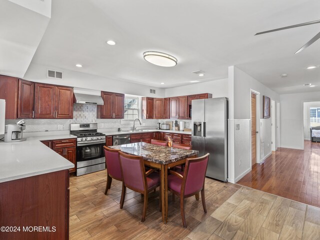 305 Franklin Ave, Seaside Heights, NJ 08751 - kitchen with appliances with stainless steel finishes, wall chimney range hood, a sink, decorative backsplash, and light wood-style floors