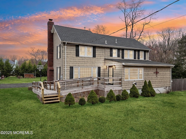 1592 W Front St, Lincroft, NJ 07738 - back of house at dusk featuring a chimney, a shingled roof, a lawn, and a wooden deck