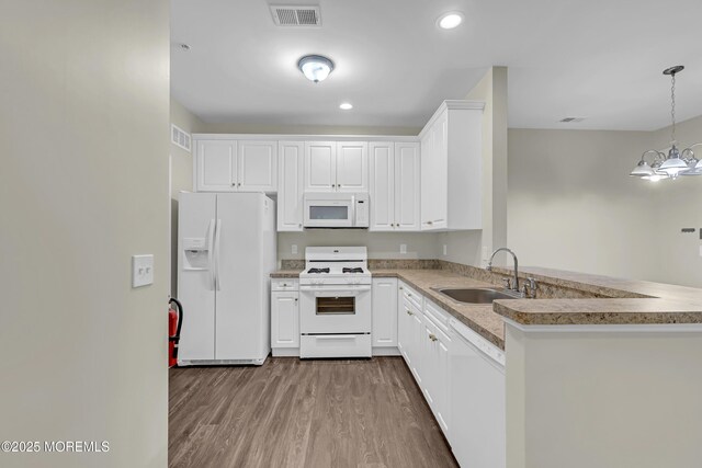 113 Sophee Ln, Lakewood, NJ 08701 - kitchen featuring white appliances, a sink, wood finished floors, a peninsula, and white cabinets