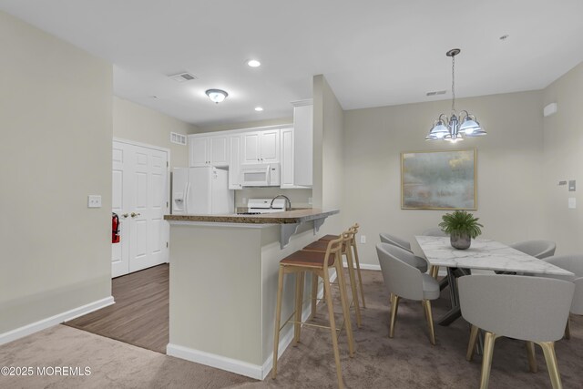 113 Sophee Ln, Lakewood, NJ 08701 - kitchen with white appliances, a chandelier, baseboards, a peninsula, and white cabinets