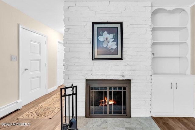 7 E Parkway Pl, Holmdel, NJ 07733 - detailed view of a baseboard radiator, a lit fireplace, and wood finished floors