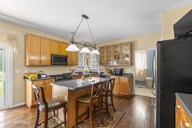 23 Emma Ln, Jackson, NJ 08527 - kitchen featuring appliances with stainless steel finishes, dark countertops, a kitchen breakfast bar, dark wood-style floors, and glass insert cabinets