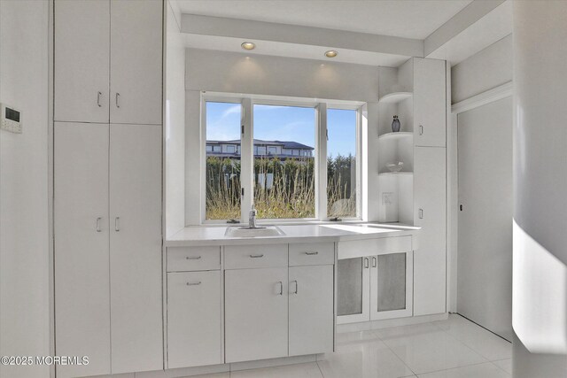 58 Ocean Ave, Deal, NJ 07723 - kitchen with a sink, open shelves, light countertops, white cabinetry, and light tile patterned floors