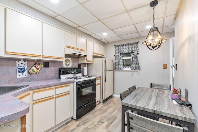 164 Holly St, Port Reading, NJ 07064 - kitchen featuring black gas range, a chandelier, light wood-type flooring, under cabinet range hood, and recessed lighting