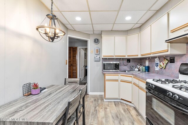 164 Holly St, Port Reading, NJ 07064 - kitchen with gas range, stainless steel microwave, a sink, light wood finished floors, and a chandelier