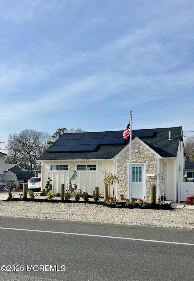 470 Mantoloking Rd, Brick, NJ 08723 - view of front of house featuring roof mounted solar panels, a shingled roof, stone siding, and board and batten siding