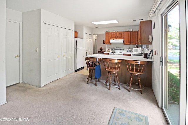 612 Petunia Ln S, Whiting, NJ 08759 - kitchen with white appliances, extractor fan, a peninsula, light colored carpet, and brown cabinetry