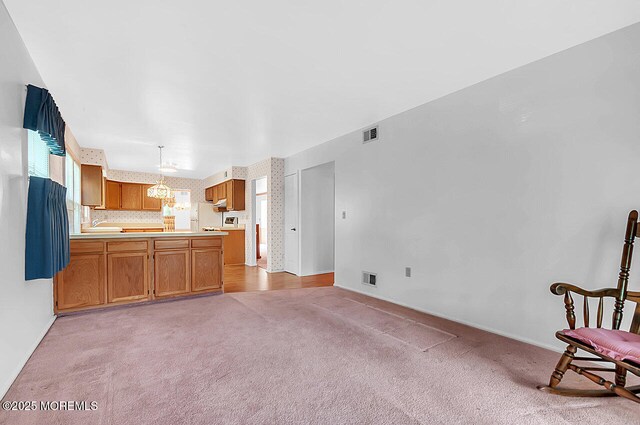 62 Woodshill Dr S, Lakewood, NJ 08701 - kitchen with a chandelier, light colored carpet, light countertops, brown cabinetry, and baseboards