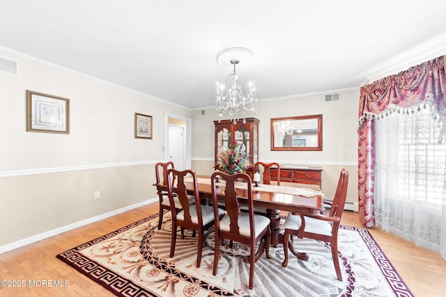 21 Tanglewood Pl, Monroe, NJ 08831 - dining room with light wood-style flooring, a chandelier, crown molding, a baseboard heating unit, and baseboards