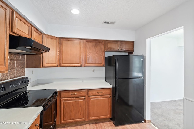 117 Northrup Dr, Brick, NJ 08724 - kitchen featuring black appliances, under cabinet range hood, a textured ceiling, light countertops, and brown cabinetry