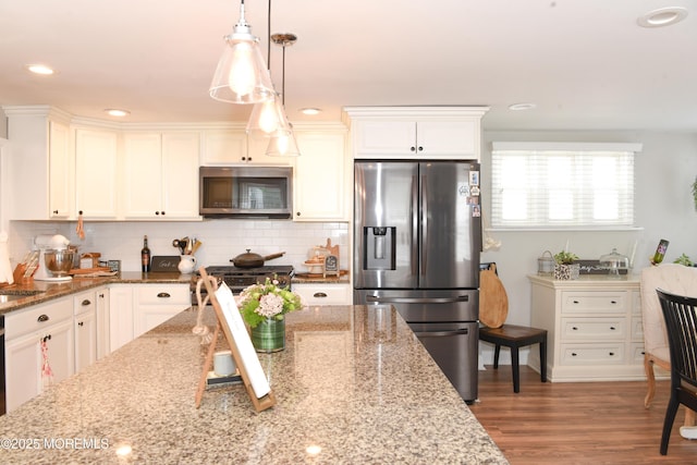 202 Main St, Matawan, NJ 07747 - kitchen with appliances with stainless steel finishes, tasteful backsplash, pendant lighting, wood finished floors, and white cabinetry