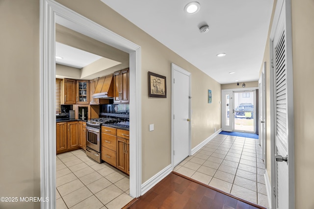 152 Redpine Loop, Old Bridge, NJ 08857 - kitchen with stainless steel range with gas cooktop, brown cabinets, custom range hood, dark countertops, and baseboards