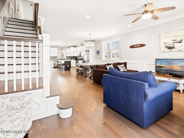 29 7th Ave Unit B, Seaside Heights, NJ 08751 - living room with ornamental molding, stairs, a ceiling fan, a chandelier, and wood finished floors
