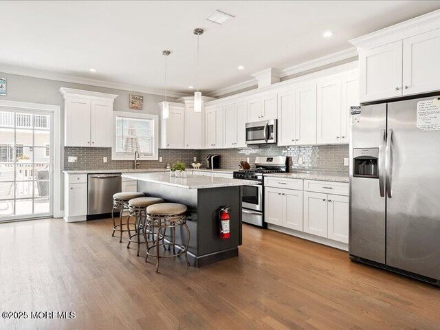 29 7th Ave Unit B, Seaside Heights, NJ 08751 - kitchen with appliances with stainless steel finishes, white cabinets, tasteful backsplash, a kitchen island, and ornamental molding
