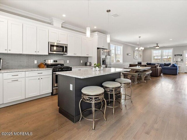 29 7th Ave Unit B, Seaside Heights, NJ 08751 - kitchen with stainless steel appliances, crown molding, a center island, white cabinetry, and a breakfast bar area