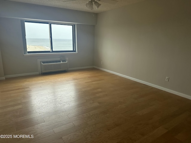 45 Ocean Ave Unit 8D, Monmouth Beach, NJ 07750 - spare room featuring a wall mounted AC, wood finished floors, ceiling fan, baseboards, and a textured ceiling