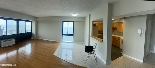 45 Ocean Ave Unit 8D, Monmouth Beach, NJ 07750 - unfurnished living room featuring a wall mounted air conditioner, baseboards, light wood-style floors, and a textured ceiling