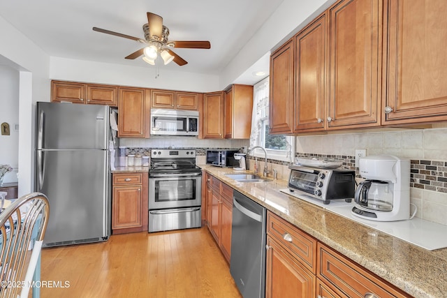 5 Lodge Ct, Brick, NJ 08724 - kitchen with appliances with stainless steel finishes, a sink, brown cabinetry, ceiling fan, and light stone countertops