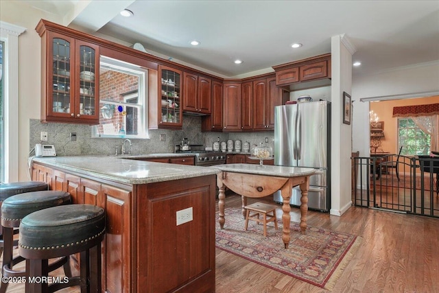 2 Warrenton Ln, Colts Neck, NJ 07722 - kitchen with stainless steel appliances, a peninsula, glass insert cabinets, a breakfast bar, and wood finished floors