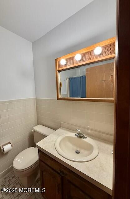 1301 SW Central Ave Unit B8, Seaside Park, NJ 08752 - full bathroom with tile walls, vanity, toilet, a shower with shower curtain, and wainscoting