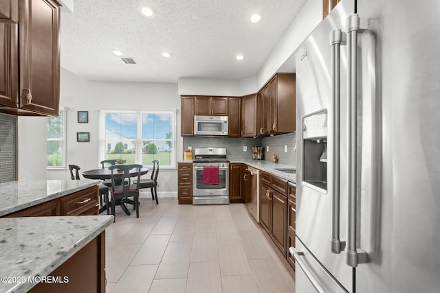 24 Birmingham Ln, Monroe, NJ 08831 - kitchen featuring stainless steel appliances, decorative backsplash, recessed lighting, light stone counters, and a textured ceiling