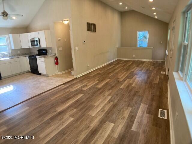 273 Stuart St, Howell, NJ 07731 - kitchen with black range with electric stovetop, stainless steel microwave, healthy amount of natural light, white cabinets, and high vaulted ceiling