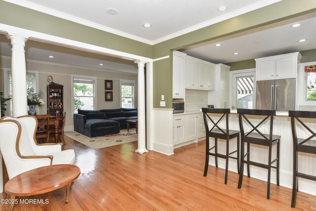 51 Clay St, Fair Haven, NJ 07704 - kitchen with appliances with stainless steel finishes, ornate columns, white cabinets, light wood-style floors, and ornamental molding