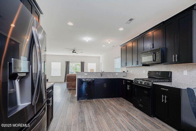 11 Starry Ln, Barnegat, NJ 08005 - kitchen with black appliances, a peninsula, light wood-style floors, tasteful backsplash, and light stone countertops