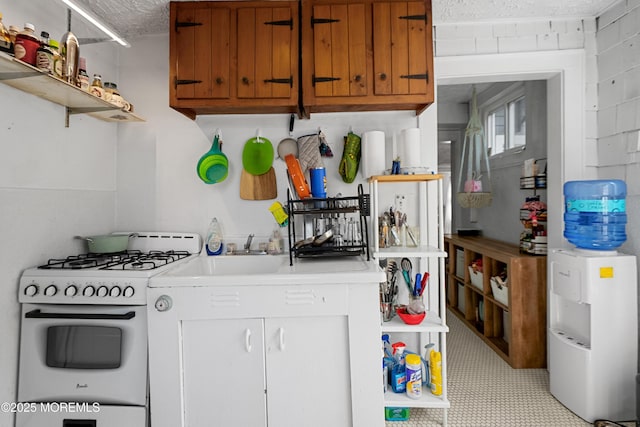 31 Riverside Ave, Red Bank, NJ 07701 - kitchen featuring white gas range, open shelves, light countertops, a textured ceiling, and brown cabinets