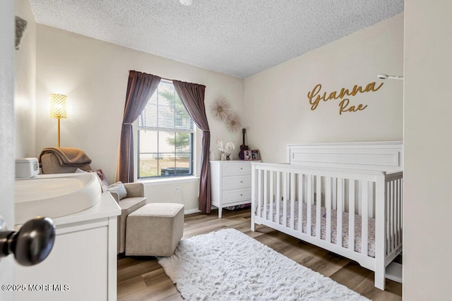 305 Daisy Ct, Jackson, NJ 08527 - bedroom with a crib, a textured ceiling, and wood finished floors