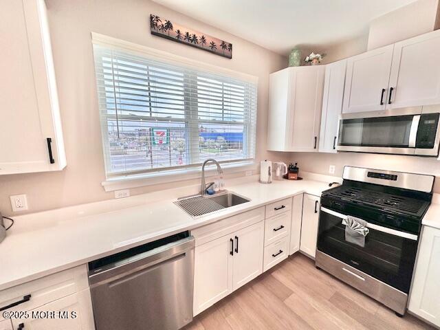 64 Sheridan Ave Unit A, Seaside Heights, NJ 08751 - kitchen featuring appliances with stainless steel finishes, a sink, white cabinets, light wood finished floors, and light countertops