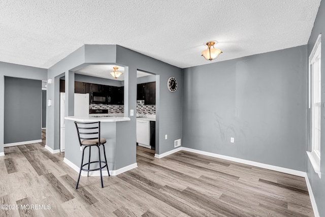 113 Whispering Oaks Way, Jackson, NJ 08527 - kitchen featuring black microwave, a breakfast bar area, light wood-style flooring, white dishwasher, and light countertops