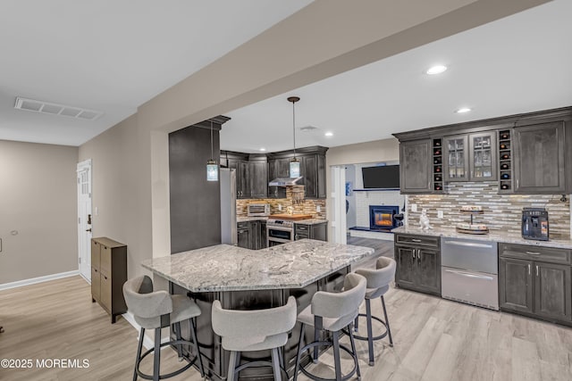 103 Idlewild Ln, Aberdeen, NJ 07747 - kitchen featuring light wood-style flooring, decorative backsplash, a breakfast bar area, light stone counters, and recessed lighting