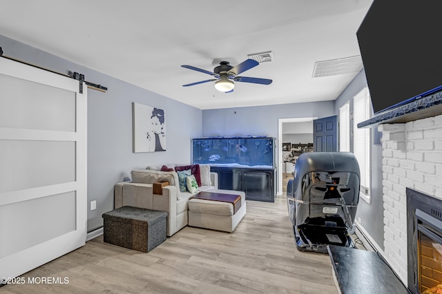 103 Idlewild Ln, Aberdeen, NJ 07747 - living room with ceiling fan, a brick fireplace, light wood finished floors, and a barn door