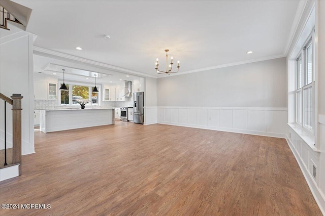 1119 Northstream Pkwy, Point Pleasant, NJ 08742 - unfurnished living room featuring a chandelier, stairs, ornamental molding, a wainscoted wall, and wood finished floors