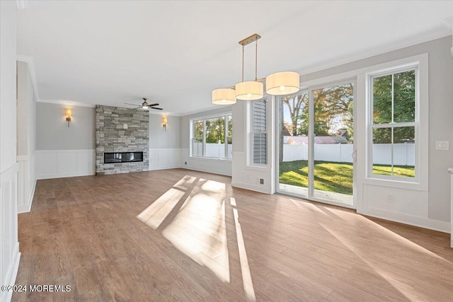 1119 Northstream Pkwy, Point Pleasant, NJ 08742 - unfurnished living room with ornamental molding, a ceiling fan, a stone fireplace, wainscoting, and wood finished floors