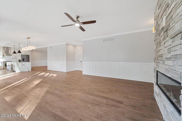 1119 Northstream Pkwy, Point Pleasant, NJ 08742 - unfurnished living room with ornamental molding, a stone fireplace, ceiling fan, wood finished floors, and a wainscoted wall