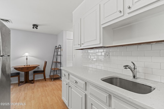 1036A Aberdeen Dr, Lakewood, NJ 08701 - kitchen with white cabinetry, freestanding refrigerator, tasteful backsplash, light wood-style floors, and light stone countertops