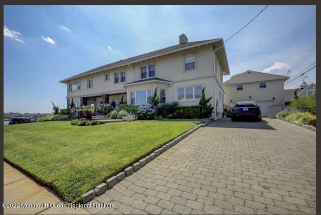 1 S Ocean Ave, Loch Arbour, NJ 07711 - view of front of home featuring decorative driveway, a chimney, a front yard, stucco siding, and a garage
