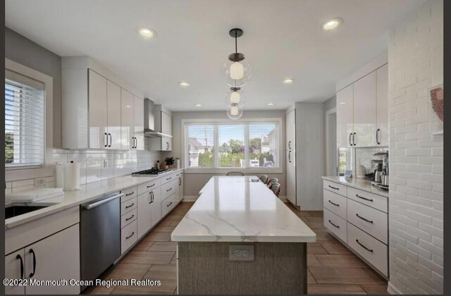 1 S Ocean Ave, Loch Arbour, NJ 07711 - kitchen featuring dishwasher, a center island, decorative backsplash, wall chimney exhaust hood, and white cabinetry