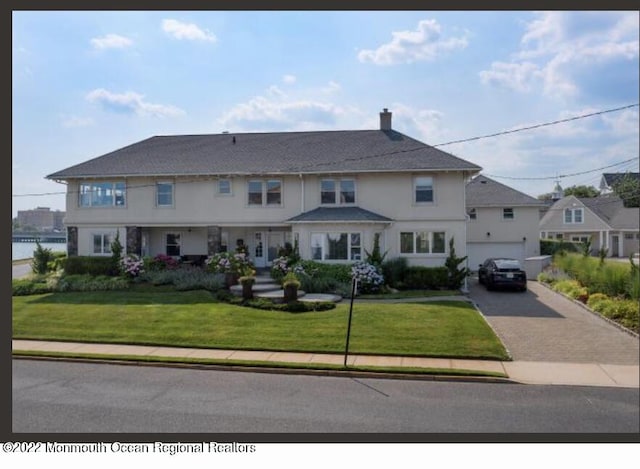 1 S Ocean Ave, Loch Arbour, NJ 07711 - view of front of home with driveway, a front lawn, a chimney, and an attached garage