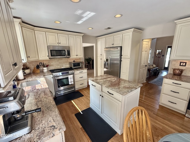 44 Diamond Ln, Howell, NJ 07731 - kitchen with appliances with stainless steel finishes, a center island, tasteful backsplash, light stone countertops, and wood finished floors